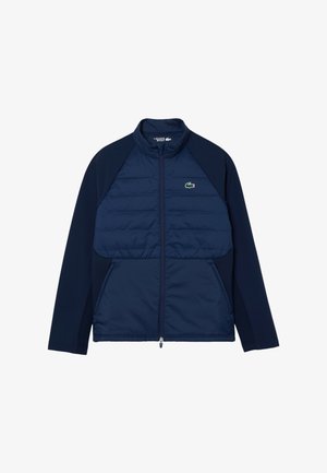 Chaqueta navy con un frente acolchado, mangas lisas, cuello alto y cierre de cremallera completo. Presenta un pequeño logo verde en el lado izquierdo del pecho.