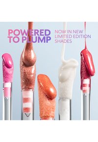 Fem lipgloss-applikatorer med ulike levende nyanser og teksturer som drypper fra tuppene deres mot en lys bakgrunn.