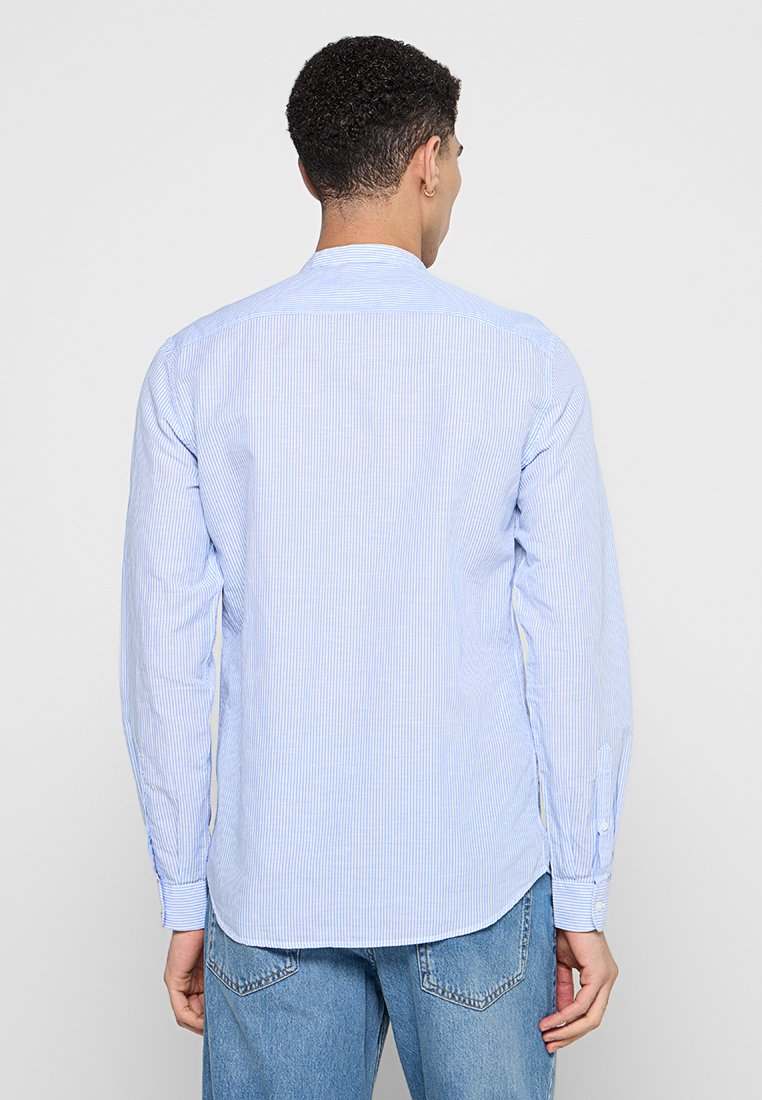 Camicia button-up a righe blu con maniche lunghe e orlo curvo, realizzata in tessuto leggero. Presenta un collo standard e polsini con bottoni.