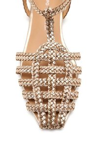 Sandal in metallo dorato intrecciato con motivo a crisscross, design T-strap, suola piatta e interno liscio.