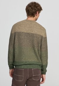 Maglione lavorato a maglia in tonalità terrose di marrone e verde, caratterizzato da un collo rotondo e polsini e orlo a costine. Finitura morbida e testurizzata.