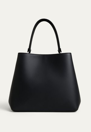 Μαύρη δερμάτινη τσάντα χειρός με στρογγυλεμένο σχήμα τραπεζοειδούς και ένα ενιαίο καμπυλωτό λουρί ώμου, εμφανίζεται σε απλό φωτεινό φόντο.