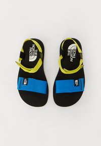 Mustad mustad neon kollaste rihmade ja siniste kangakasutustega, millel on tekstuuriga põhi ja logo prinditud jalatsi sisse.