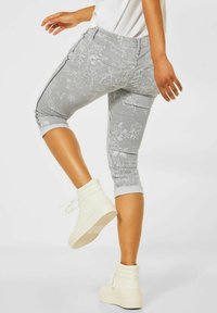 Grau-weiße gemusterte Capri-Hosen mit schlanker Passform und umgekrempelten Säumen. Getragen mit weißen Sneakern im hohen Design, die einen modernen, lässigen Look unterstreichen.