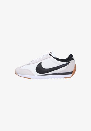 Zapatillas Nike con parte superior de cuero blanco y gamuza, acentos negros, suela de goma con suela de caucho natural, y un diseño clásico de cierre de cordones.