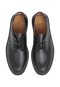 Scarpe in pelle nera con una finitura liscia, punta arrotondata, cuciture bianche a contrasto lungo la suola e design con lacci. Logo del marchio visibile all'interno.