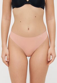 Lichtroze katoenen thong met een glad, naadloos ontwerp. Beschikt over een smalle tailleband en een klein wit Calvin Klein-logo aan de voorkant.