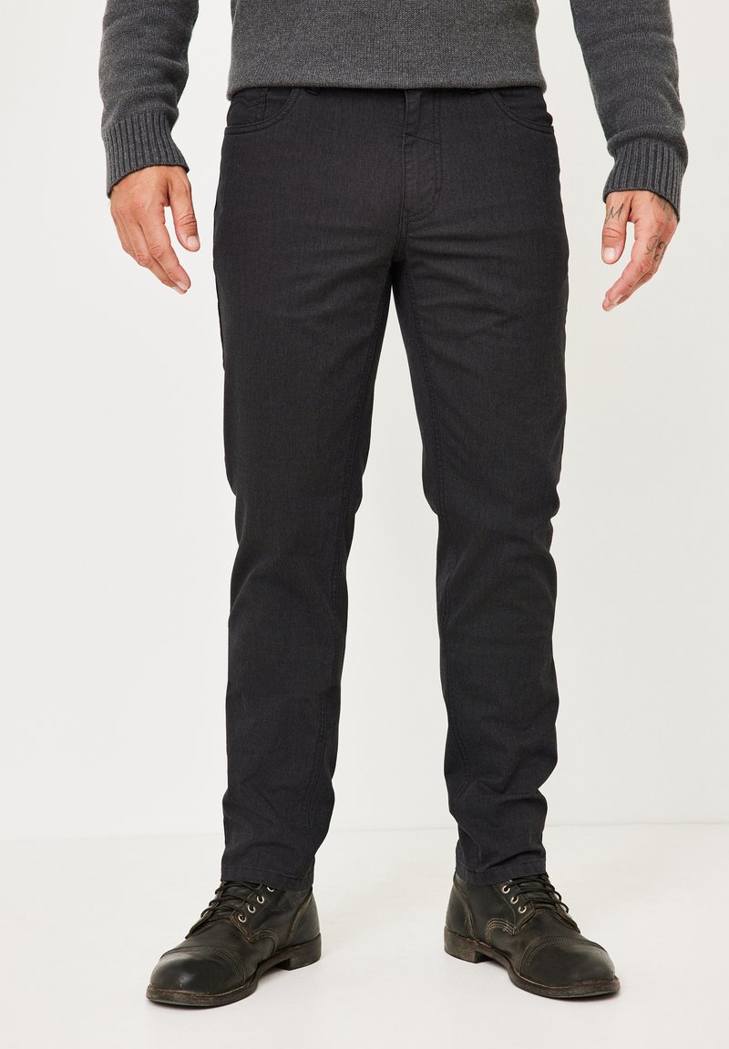 Black denim pants with a textured design, slim fit, five-pocket style, and stitched accents; paired with dark leather boots.