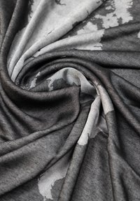 Tessuto a cascata in tonalità di nero e grigio con un design testurizzato e stampato. Drape morbido con una superficie liscia. Motivo astratto su tutta la superficie.