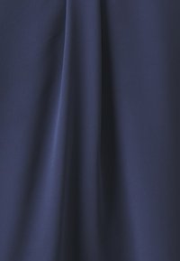 Tessuto blu scuro con una finitura liscia e opaca, che cade dolcemente con leggere pieghe creando una sottile texture e profondità.