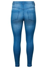 Jeans ajustados de denim azul desgastado, con una cinturilla limpia, dos bolsillos traseros y una textura suave. Ajustados desde la cintura hasta el tobillo.