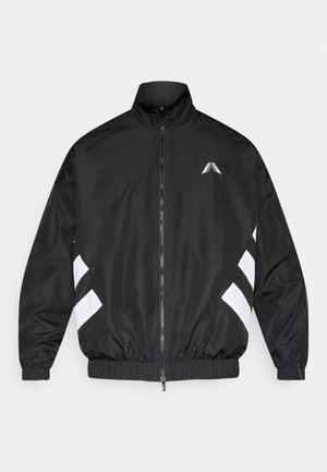 Chaqueta cortavientos negra, con cuello alto, cremallera frontal, puños elásticos y rayas diagonales blancas en las mangas.