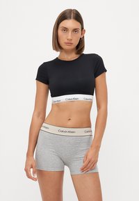 Svart kortermet crop top med Calvin Klein-logo bånd, parret med grå bomullsbokse med en kontrasterende midjebånd.