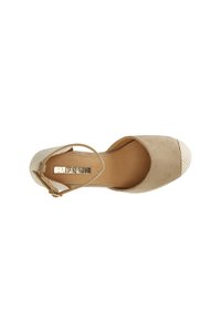 Beige Wildleder-Ankle-Strap-Schuh mit runder Zehenpartie, gewebtem weißen Zehenkappeneinsatz und flacher, glatter Sohle. Eingravierte Markenbezeichnung auf der Innensohle sichtbar.