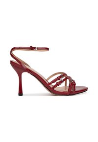Červené lakované sandále na vysokom podpätku s tenkým remienkom okolo členka, otvorenou špičkou a tkaným predným dizajnom. Majú elegantný ihličkový podpätok.