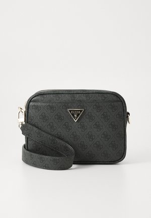 Kleine zwarte Guess crossbodytas met subtiel patroon, driehoekig metalen logo en brede verstelbare band op een witte achtergrond.