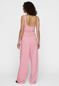 Lichtroze geribbelde tanktop met een ronde rug, gecombineerd met wijde roze sweats met een achterzak en een gestructureerde afwerking.