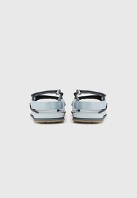 Sandales à straps bleus avec des sangles réglables gris foncé, semelles en caoutchouc et dessous de pieds texturés. Présente un design simple et un style minimaliste.
