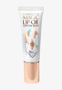 Charlotte's Magic Lip Oil packaging features a white tube with a crystal design, iridescent accents, and a rose gold cap. Text includes brand name and product type.