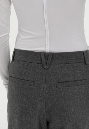 Grijze broek met een dunne streep, voorzien van twee achterzakken, een platte tailleband en een subtiele textuur. Gemaakt met een wit langslaven top.