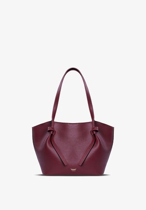 Burgundy tote bag with a textured leather finish, featuring a wide silhouette, knotted handle details, and a metallic logo accent.