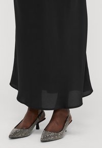 Sorte slingback-sko med spiss tå, dekorert med sølvglitter for en teksturert, glitrende finish. Lav kitten-hæl.
