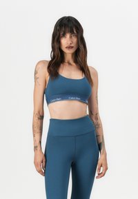 Blå sportsbh og høytlivsleggings fra Calvin Klein, laget av glatt stoff med en logobånd og en tettsittende design.