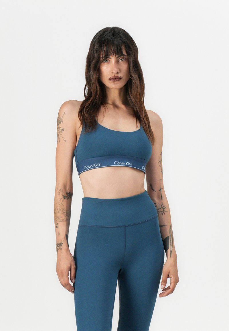 Blå sportsbh og høytlivsleggings fra Calvin Klein, laget av glatt stoff med en logobånd og en tettsittende design.