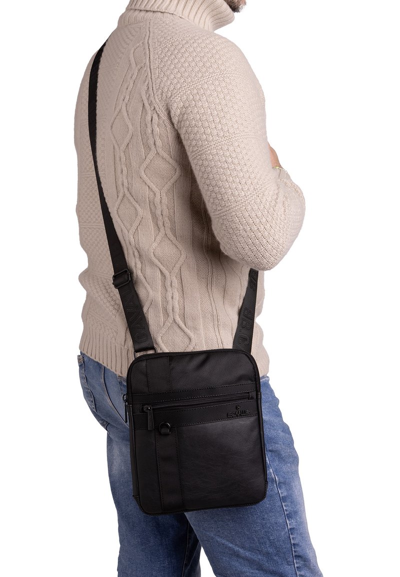 Borsa a tracolla nera in pelle e tessuto testurizzato. Presenta spallacci regolabili, tasche con zip multiple e una forma rettangolare.