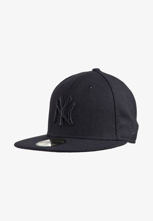 Gorra negra de béisbol de los New York Yankees con visera plana y logo bordado en la parte frontal, vista ligeramente de lado.
