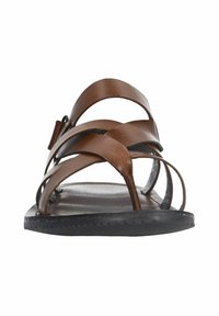 Brown leather sandal with multiple horizontal straps, textured black rubber sole, and a flat design. Open toe with a minimalist look.