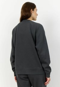 Sweat-shirt gris foncé avec un col ras du cou, des poignets et un ourlet côtelés. Il présente une coupe décontractée et un tissu doux et texturé.