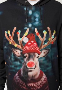 Sudadera negra con un gráfico de un reno con nariz roja, gorro rojo y suéter acogedor. El diseño incluye luces de colores en los cuernos.