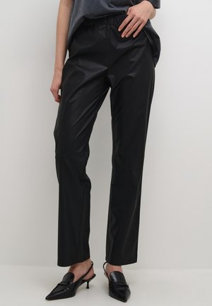 Zwarte faux leren broek met een relaxte pasvorm, elastische tailleband en een gladde textuur. Gecombineerd met zwarte spitse slingback hakken.