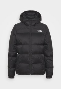 Svart vadderad vinterjacka med huva och framsida dragkedja, med The North Face-logotyp på bröstet. Jackan har sidofickor och elastiska ärmslut.