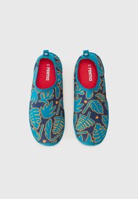 Blå slip-on sko med en mørk baggrund, der har et bladmønster i turkis og orange. Indersiden har en rød tekstur med logo.