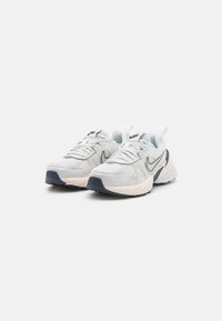 Atletiska skor med ett vitt mesh-överkropp, ljusblå accenter, mörkblå yttersula och en vadderad sula med en framträdande häl.