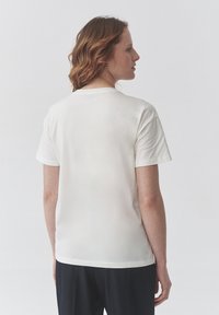 Bílá bavlněná tričko s krátkým rukávem, kulatým výstřihem a hladkým povrchem. Má jednoduchý, nezdobený design a rovný lem.