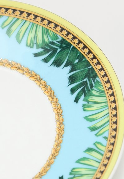 Bord d'assiette en porcelaine avec fond bleu, feuilles de palmier vertes, bordure intérieure ornementale dorée, et bandes décoratives extérieures jaunes et noires.