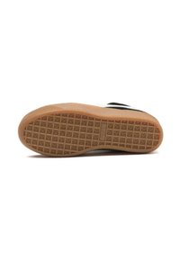 Suola di una sneaker bianca e nera con una suola in gomma naturale caratterizzata da un motivo a griglia per migliorare la trazione.