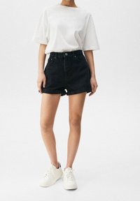 Czarne szorty z denimu z podwiniętym brzegiem, w połączeniu z białym, oversize'owym t-shirtem i białymi trampkami. Prosty fason z delikatnymi przeszyciami.