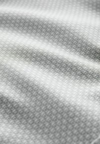 Teksturna tkanina s suptilnim geometrijskim uzorkom u svijetlosivoj boji. Materijal izgleda glatko s blagim sjajem, stvarajući dimenzionalni efekt.