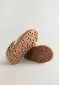 Kangaskengät leopardikuosisella pintakuvalla, jossa on vaaleanruskea kumipohja, johon on kuvioitu tekstuureja, kuten pilviä ja hymynaamoja.