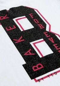 Bílý tričko s velkým černým číslem "8" s růžovými akcenty a texturovanými detaily. Pod číslem je text "BAKER FOREVER".