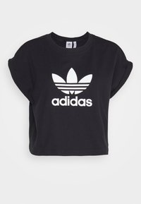 Black cropped t-shirt with folded short sleeves featuring a white Adidas trefoil logo and text centered on the front.