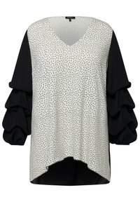 Blusa de manga larga con un estampado geométrico en blanco y negro, que presenta mangas negras con volantes y un escote en V. Corte fluido con un dobladillo asimétrico.