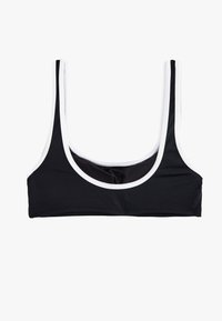 Reggiseno sportivo nero con spalline larghe, scollatura a giro e dettagli bianchi attorno alle aperture delle braccia e all'orlo inferiore. Texture del tessuto liscia.