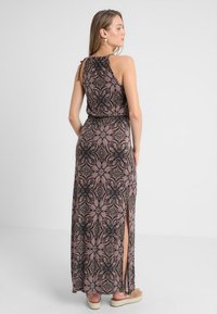 Vestido maxi en patrón floral rosa y negro, sin mangas con lazo en la espalda, que presenta una abertura lateral y un tejido texturizado. Los acentos incluyen un escote fruncido.