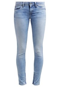 Jeans skinny de denim en azul claro, con una textura desgastada, bolsillos frontales y un ligero corte en el dobladillo.