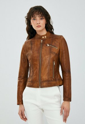 Giacca da motociclista in pelle marrone con colletto alto, chiusura con zip e due tasche laterali. Presenta cuciture decorative e dettagli in metallo argentato.